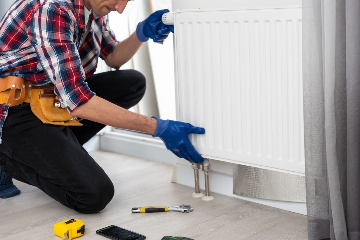 A professional HVAC technician repairing a radiator heater